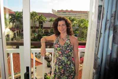 Breast cancer survivor Jill enjoying a vacation, standing on a scenic hotel balcony.