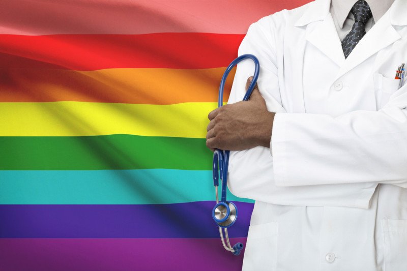 Doctor standing in front of a rainbow flag