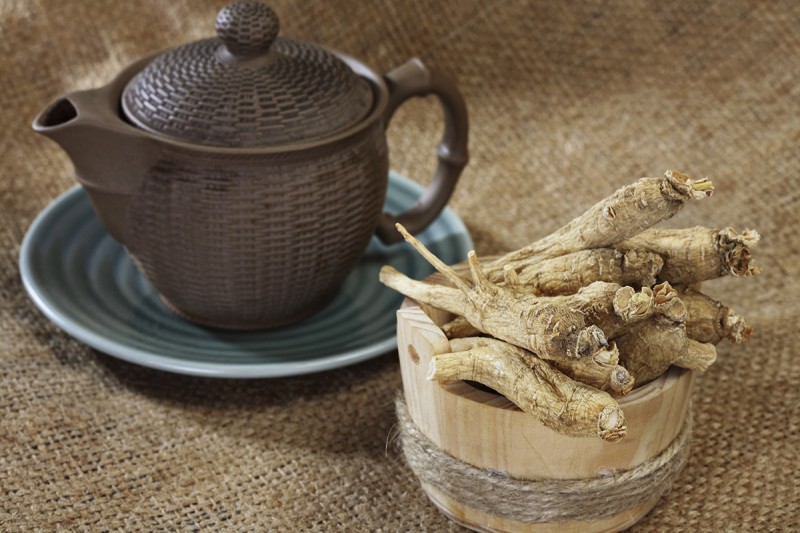 A bowl of ginseng root sitting next to a teapot.