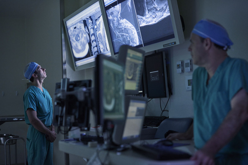 Neurosurgeons Ilya Laufer and Mark Bilsky who experts in removing spine tumors are monitoring numerous screens.