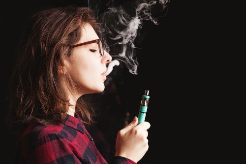 A young woman inhaling from an electronic cigarette